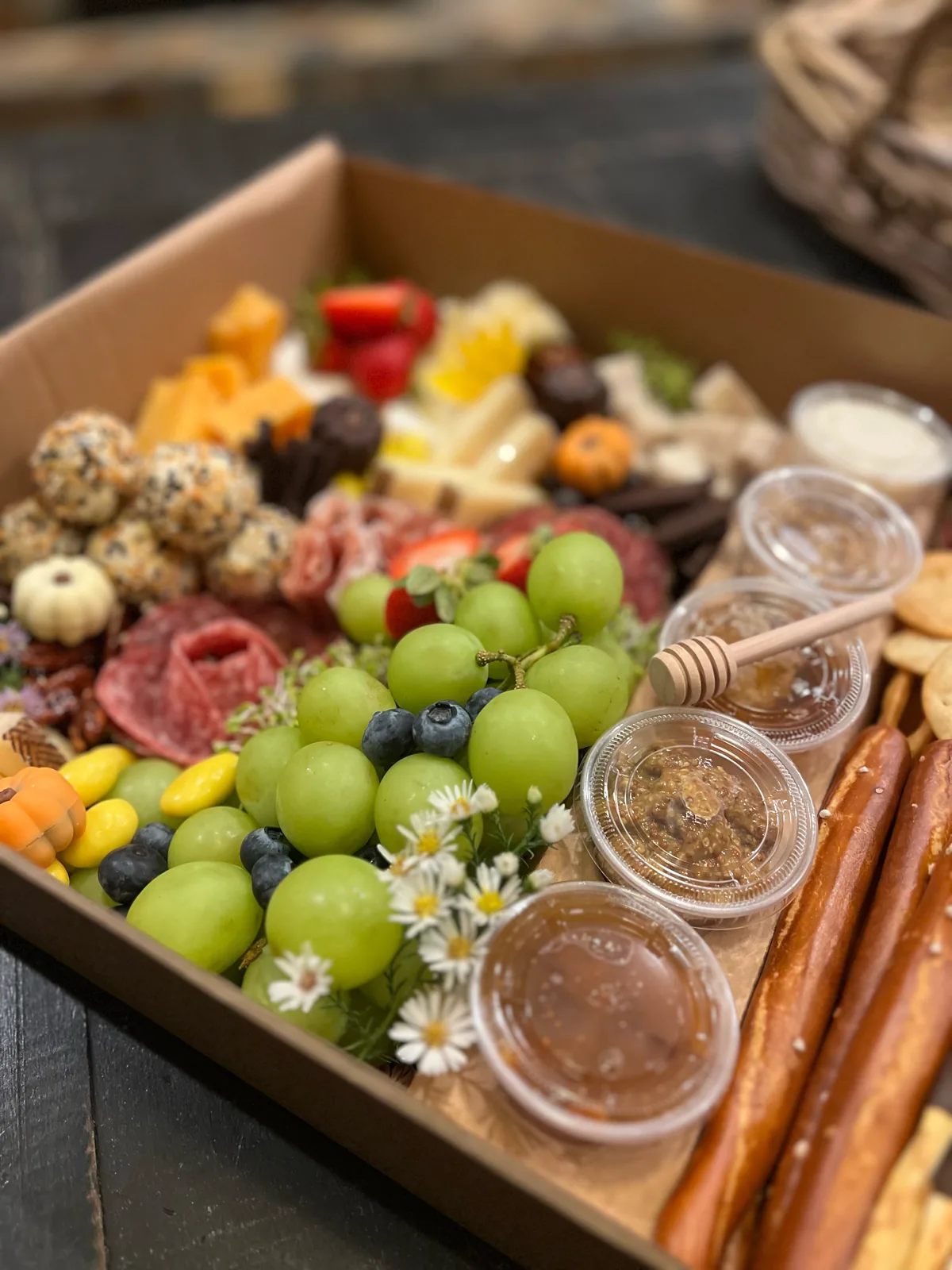 Custom charcuterie box detail with fruit, cured meats, crackers, and accompaniments