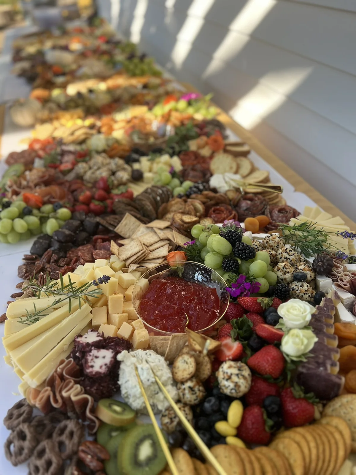 Cheeses, fruit, crackers, and preserves arranged along an October grazing table